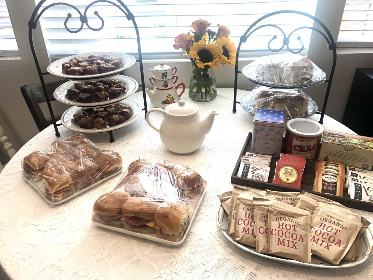 A table covered in lots of delicious sandwiches, teas, and desserts. 