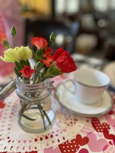 A jar of carnations with a tea cup. 